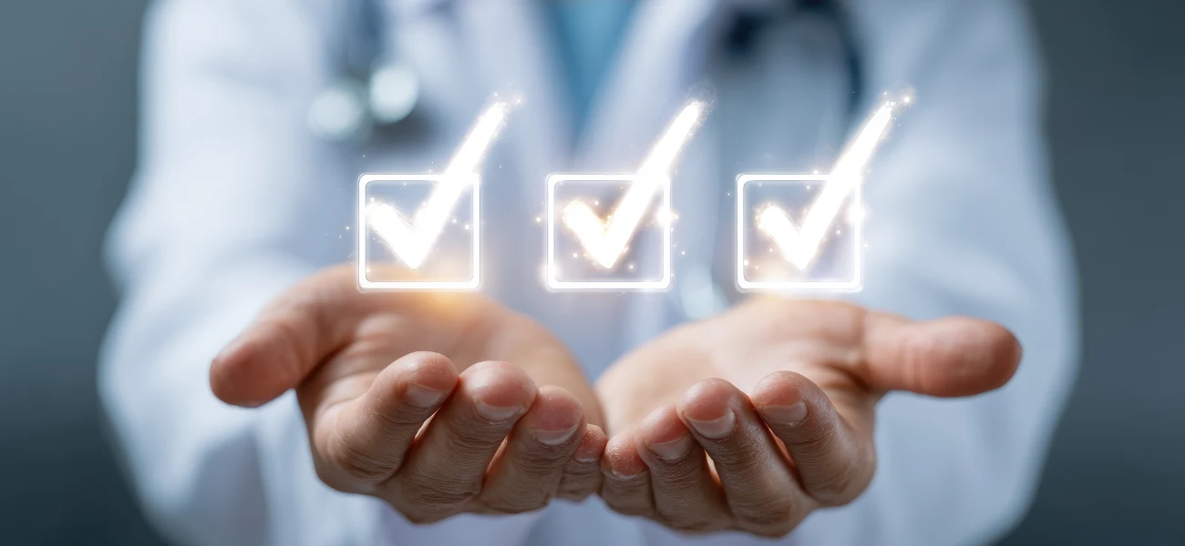 A physician in a white coat holds out cupped hands with three glowing checkmarks, representing qualities of a good doctor.